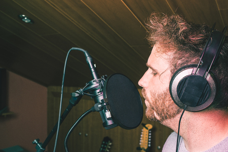 Singer singing in a music studio with microphone and headphonesの写真素材