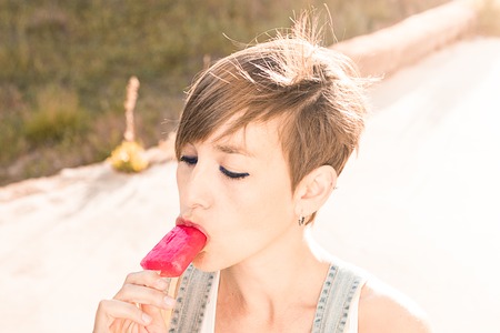 Close-up of a beautiful young woman eating an ice cream ice lolly.Strawberry flavorの写真素材