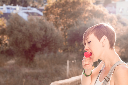 Portrait of a modern woman eating strawberry ice cream at sunset Social network style photographyの写真素材