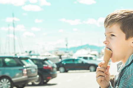 Close-up of a child eating an ice cream cone. Blond child