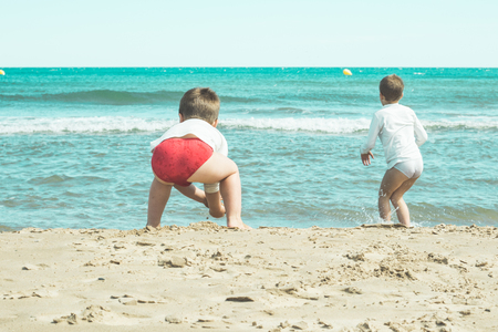 Kids playing in the sand on the beach. Several adorable little kids playing happily on the beachの写真素材