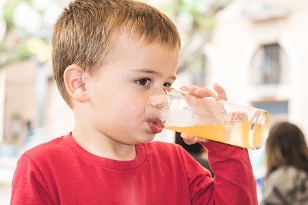 Kid drinking a soda out of a glass. Close-up of a child with a soda drink