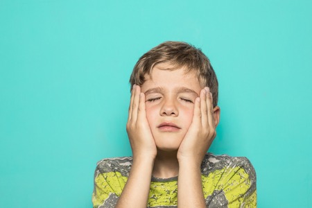 A child expressing a firing squad with his hands on his faceの写真素材