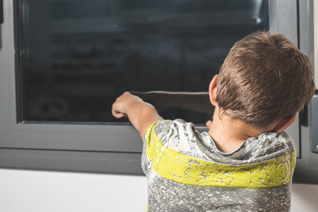 Child pointing through a window in a houseの写真素材