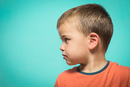 Blond boy in profile on a blue background. Profile portrait of a kidの写真素材