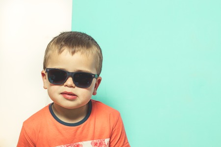 Child wearing sunglasses with a serious attitude. Blond Kid with sunglassesの写真素材