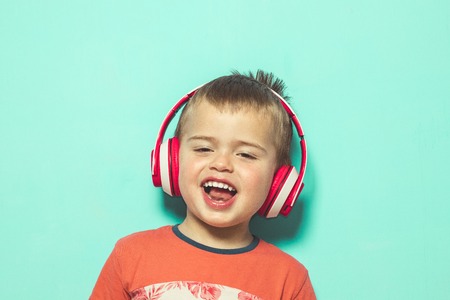 Child listening to music with headphones. Lovely Kid with music helmetsの写真素材
