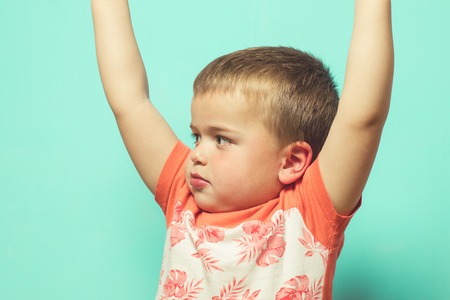 Child with arms raised on a blue backgroundの写真素材