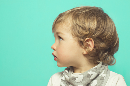 Lovely little girl on a blue background. Little girl in profileの写真素材