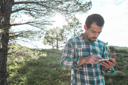 Guy looking at his cell phone in the field. Man with mobile phone in the fieldの写真素材