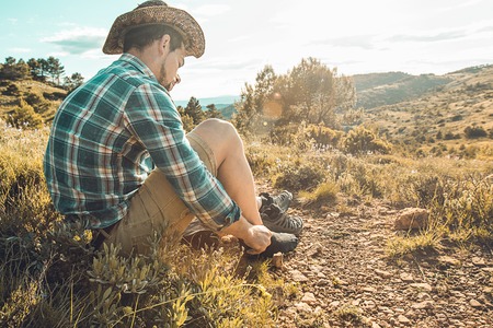 Man tying his boots on the mountain. Guy putting on some bootsの写真素材