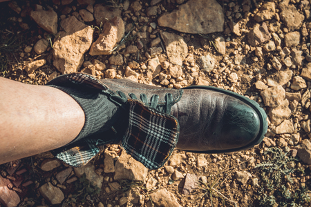 Man tying his boots on the mountain. Guy putting on some bootsの写真素材