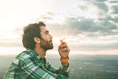 Guy smoking a thoughtful cigarette. Guy dressed casual and beardの写真素材