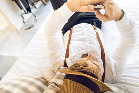 Modern Guy looking at his cell phone in bed. Modern Guy looking at his cell phone.の写真素材