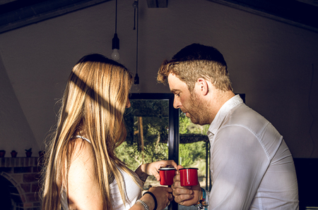 A guy and a girl looking at each other, and drinking a cup of tea. Sexy look between a guy and a girlの写真素材
