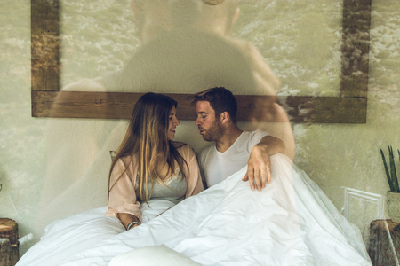 Couple of guy and girl in bed smiling and happy. Couple of girl and guy showing affection in bed. Concept of love between couplesの写真素材