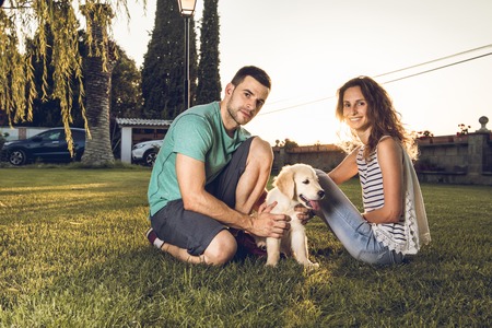 Happy couple with puppy dog in the country. Boy and girl with their adorable puppy