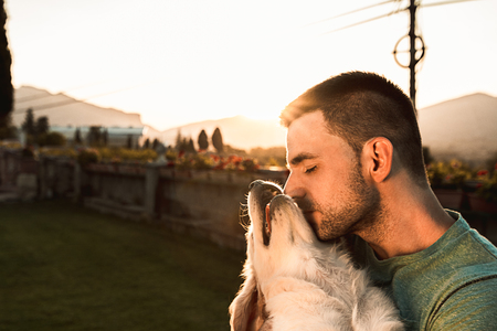 Young man with his adorable puppy dog. Concept of love between dog and manの写真素材