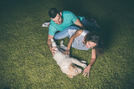 Couple playing with their puppy dog in the fieldの写真素材