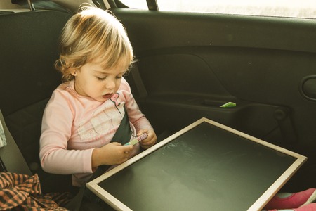 Lovely little girl in the back seat of a car. Children traveling in a car