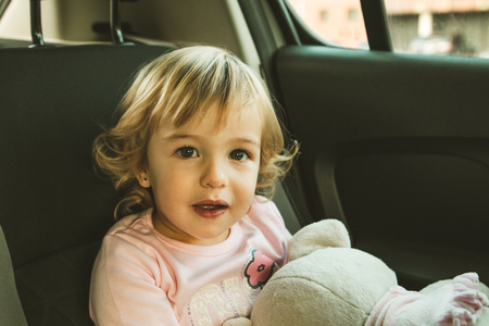 Lovely little girl in the back seat of a car. Children traveling in a carの写真素材