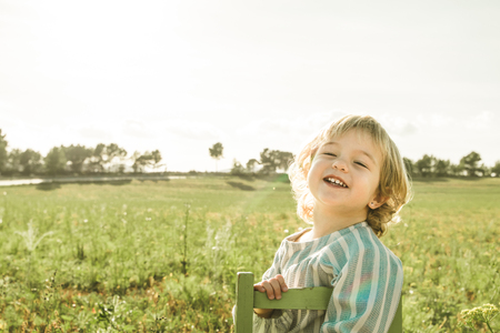 Portrait of a lovely little girl in the blonde field. Girl in a meadow with the sun behindの写真素材