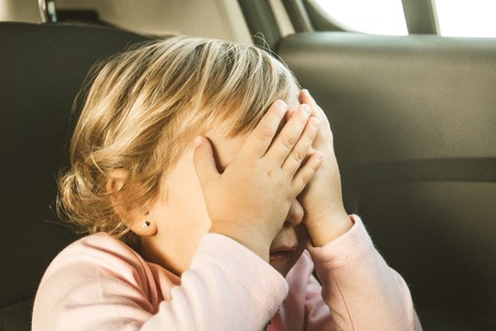 Lovely little girl in the back seat of a car. Children traveling in a carの写真素材