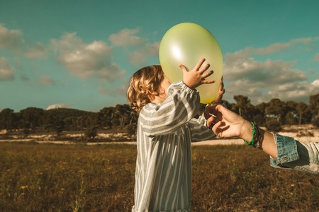 Lovely little girl playing with balloons on the field. Photo of children vintage style