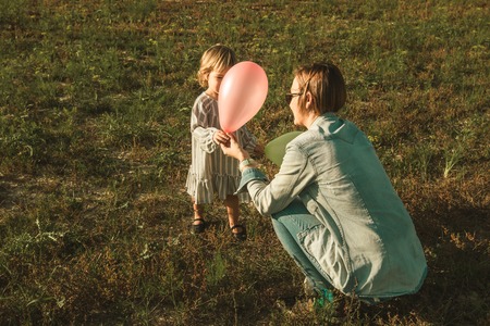 Lovely little girl playing with balloons on the field. Photo of children vintage styleの写真素材