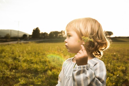 Little girl playing with plants in the field. Concept children in contact with natureの写真素材