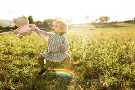 Little girl playing with a stuffed animal on the field. Concept children playing in the fieldの写真素材