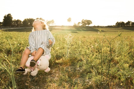 Little girl playing with a stuffed animal on the field. Concept children playing in the fieldの写真素材