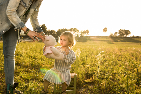 Little girl playing with a stuffed animal on the field. Concept children playing in the fieldの写真素材
