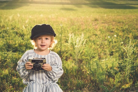 Portrait of a little girl taking pictures with a camera. Concept of adorable children playing