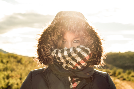 Portrait of a young woman with a coat and hood onの写真素材