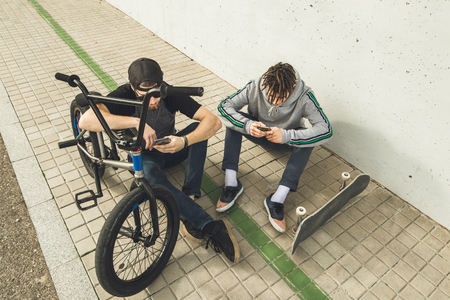 Young guys looking at the cell phone on the street. Concept of lifestyle of young people with technologyの写真素材
