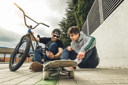 Young guys looking at the cell phone on the street. Concept of lifestyle of young people with technologyの写真素材
