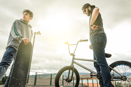 Two friends around town on bicycles and skateboards. Lifestyle of young people on the streetの写真素材