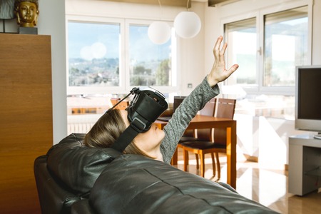A young woman at home with VR glasses. Virtual Reality Goggles Conceptの写真素材