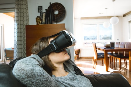 A young woman at home with VR glasses. Virtual Reality Goggles Concept