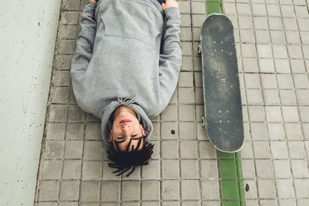 Portrait of a guy with a skateboard. Skateboarder in the street of a cityの写真素材