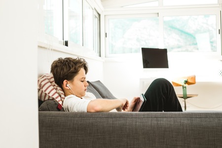 Boy looking at a tablet. Child watching a tablet at home. Concept of children with technologyの写真素材