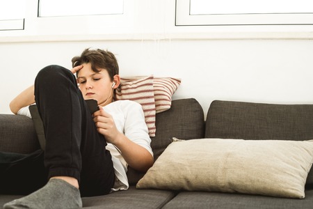 Boy looking at a tablet. Child watching a tablet at home. Concept of children with technologyの写真素材