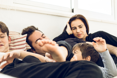A happy family playing and smiling on the couch at home. Concept of a cheerful family with childrenの写真素材