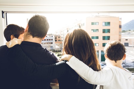A family with kids hugging and looking out the window. Concept of a happy large familyの写真素材