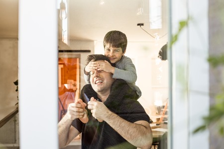 Father playing with his son on his shoulders at home. Concept of love and happiness between child and fatherの写真素材