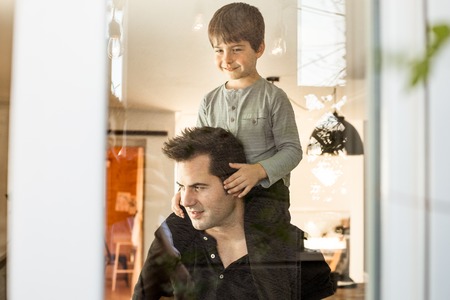 Father playing with his son on his shoulders at home. Concept of love and happiness between child and fatherの写真素材