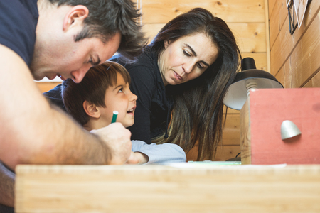 Child painting a picture at home with his parents. Father and mother assisting their son in drawing a picture.の写真素材