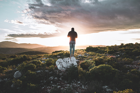 Young man in the field watching a sunset. Concept freedom and inspirationの写真素材