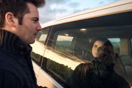 Couple looking at each other through the car window. Concept of happy and smiling boyfriendsの写真素材